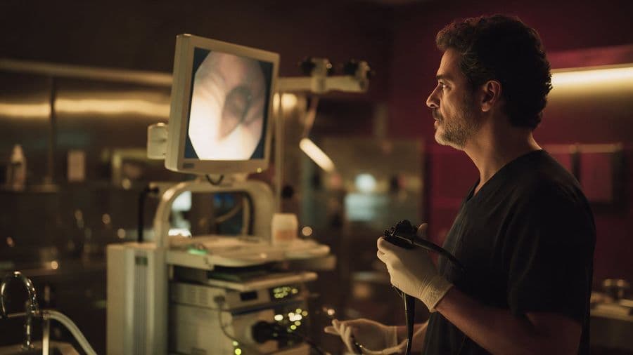 Gastroenterologista segura um endoscópio diante do monitor da sala de exames